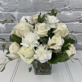 White rose and carnation bouquet in a square glass vase
