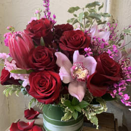 Red roses and a pale orchid in a green striped vase