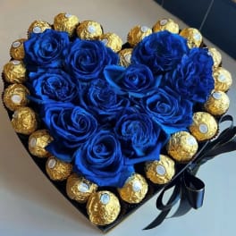 Heart-shaped box with blue roses and gold-wrapped chocolates
