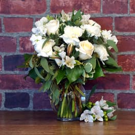 White roses and carnations in a glass vase with a matching boutonniere