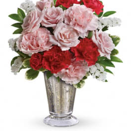 Pink and red carnations with white filler in a silver vase