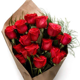 Hand-tied bouquet of red roses wrapped in brown kraft paper