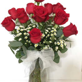Red roses arranged in a glass vase with a white ribbon