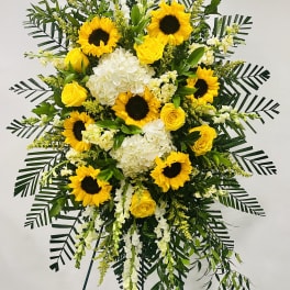 Tall standing floral spray with sunflowers, yellow roses, and white blooms