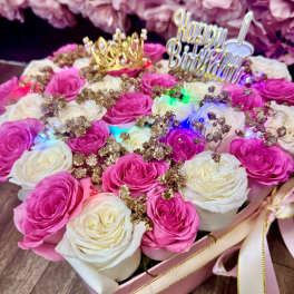 Pink and white roses in a gift box with a birthday topper and crown