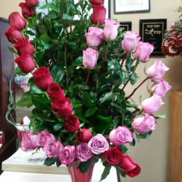 Tall arrangement of red and pink roses in a glass vase