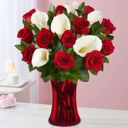 Red roses and white calla lilies in a red glass vase