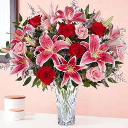 Bouquet of pink lilies and red roses in a clear glass vase