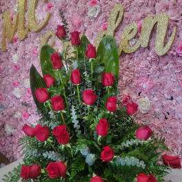 Red rose arrangement against a pink floral wall with gold lettering