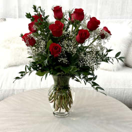 Red roses arranged in a clear glass vase with baby's breath