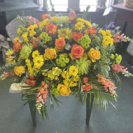 Large bouquet of yellow and orange flowers with greenery on a table