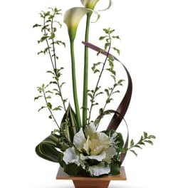 Tall floral arrangement with white calla lilies in a wooden container