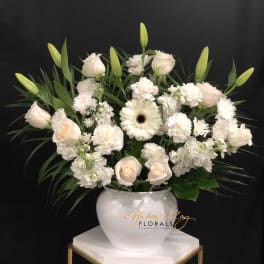 White roses and lilies arranged in a white vase