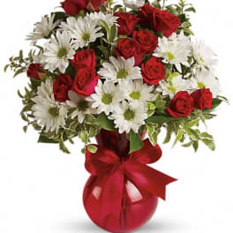 Red roses and white daisies in a red vase with a ribbon