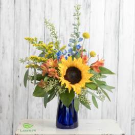 Sunflower bouquet in a blue glass vase with yellow and orange accents