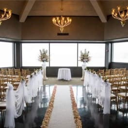 Wedding ceremony aisle with white draping and floral arrangements