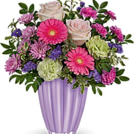 Pink and white flowers arranged in a purple vase