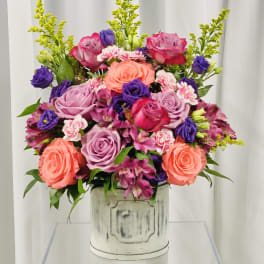 Mixed bouquet of roses, alstroemeria, and carnations in a white container