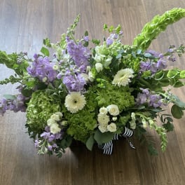 Low floral arrangement with lavender blooms, white flowers, and bright green accents