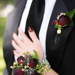 Boutonniere and wrist corsage with dark red roses and white accents