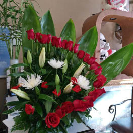 Red roses and white lilies in a large arrangement with green leaves
