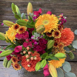 Bright mixed bouquet with yellow daisies, pink roses, orange blooms, and lily buds