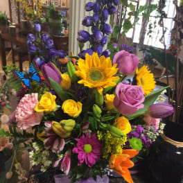 Colorful mixed bouquet in a glass vase with sunflowers, roses, and tulips
