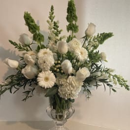 White floral arrangement in a clear glass vase with tall green spikes