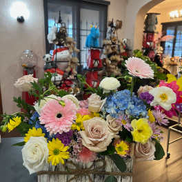 Mixed bouquet in a rustic wooden box with roses, gerbera daisies, hydrangea, and ranunculus