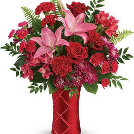 Red and pink mixed flower arrangement in a red vase