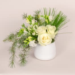 White roses and green filler in a white vase