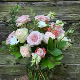 Pink and white roses in a glass vase with greenery