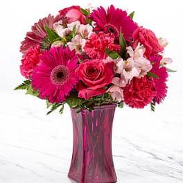 Pink mixed flower bouquet in a tall magenta vase