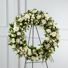 Large white floral wreath on a black easel stand