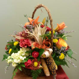 Basket arrangement with mixed flowers, corn, and a rope handle