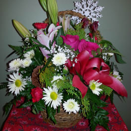Basket arrangement with lilies, roses, daisies, and a red ribbon