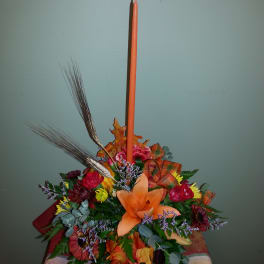 Autumn floral arrangement with an orange taper candle and mixed flowers