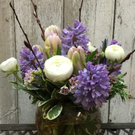 Purple and white flowers arranged in a round glass vase