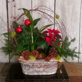 Holiday planter with red ornaments, poinsettia, and pinecones in a basket