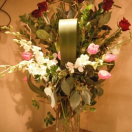 Tall bouquet of red roses and white orchids in a clear glass vase