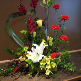 Tall floral arrangement with white lilies, red carnations, and yellow blooms