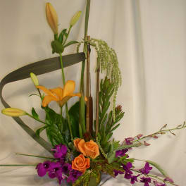 Tall floral arrangement with orange lilies, roses, and purple orchids