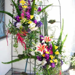Tall floral standing arrangement with lilies and mixed blooms on a metal frame