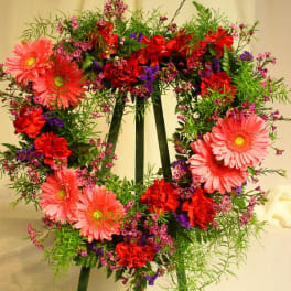 Heart-shaped floral wreath with pink gerbera daisies and red carnations