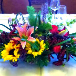 Low centerpiece with lilies, sunflowers, and roses on a banquet table