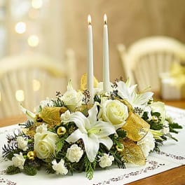 White floral centerpiece with two lit taper candles