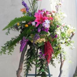 Tall floral arrangement with pink lilies and purple blooms on a stand