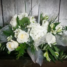 White floral arrangement with roses, hydrangeas, and lilies in a low container