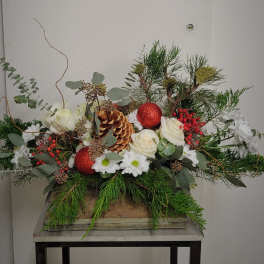 Holiday floral arrangement with white roses, daisies, pinecones, and red ornaments