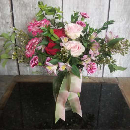 Mixed pink and red bouquet in a glass vase with a ribbon